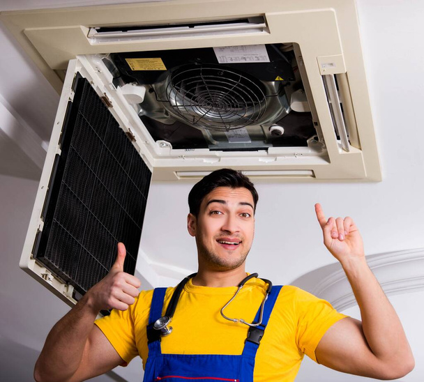 Reparador reparando la unidad de aire acondicionado del techo - Foto, imagen