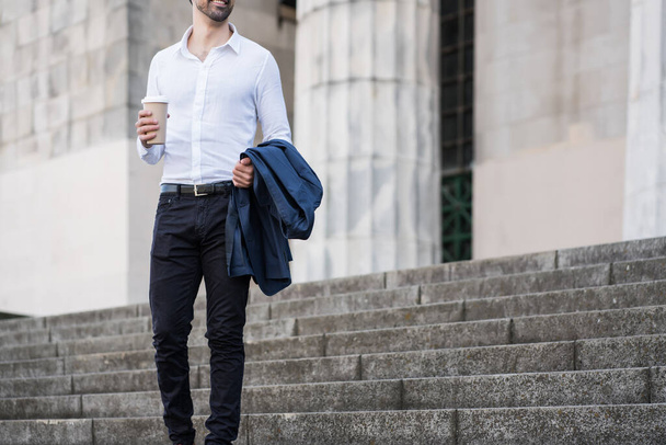 Businessman holding a cup of coffee on way to work. - Foto, afbeelding