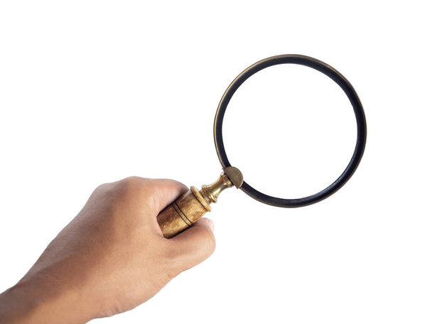Hand holding old vintage magnifying glass isolated on white background. Ancient magnifying glass made by wood and gold. - Photo, Image