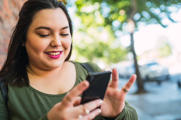 Young plus size woman using her mobile phone. - Φωτογραφία, εικόνα
