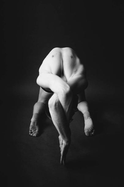 Yoga workout.  Man performs yoga asanas on dark background. Stylish studio sports photography - Valokuva, kuva