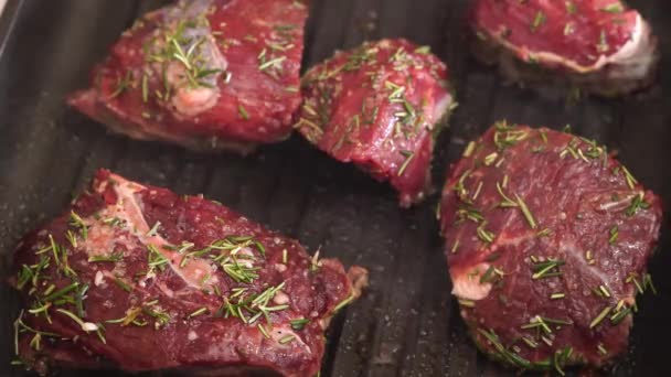 Sappige stukken rode biefstuk worden gestoomd in een grillpan en gebakken bestrooid met rozemarijn. - Video