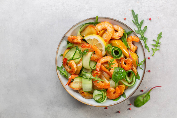 Fresh salad with grilled prawns, caramelized pears, cucumber and mixed greens, with lemon dressing.  Light grey background. Top view. - 写真・画像