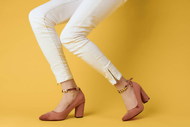 Gambe femminili pantaloni bianchi vestiti alla moda scarpe di lusso sfondo giallo - Foto, immagini