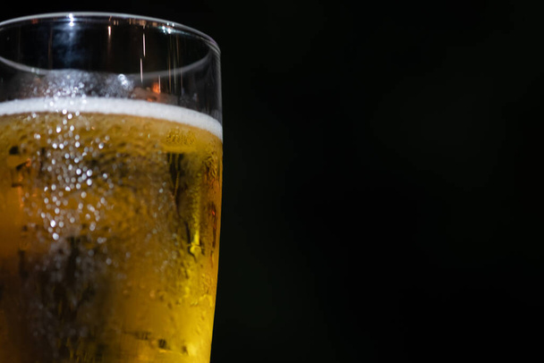 Glass of light beer on a dark background. Close up - 写真・画像