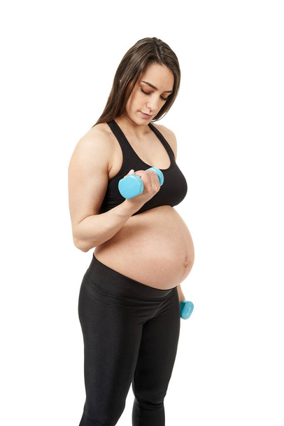 妊娠中の若い妊婦は白い背景で隔離された妊娠のための適性の練習をする - 写真・画像