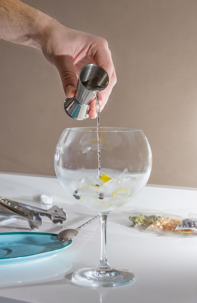 Бармен наливает напиток, чтобы приготовить джин-тоник
 - Фото, изображение