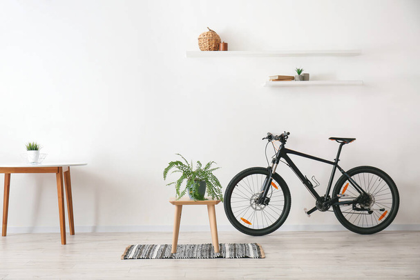 Стол с домашним растением и велосипедом в комнате - Фото, изображение