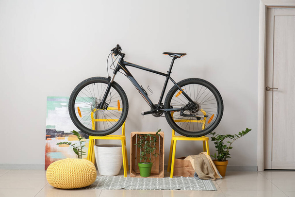 Modern chairs with bicycle near white wall in room - Photo, Image