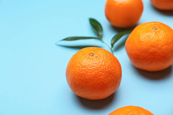 Composition with sweet tangerines and leaves on color background, closeup - Foto, Imagen