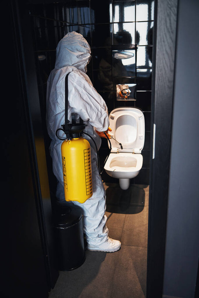 Képzett gondnok, aki a vírusellenes tisztítást végzi a nyilvános WC-ben. - Fotó, kép