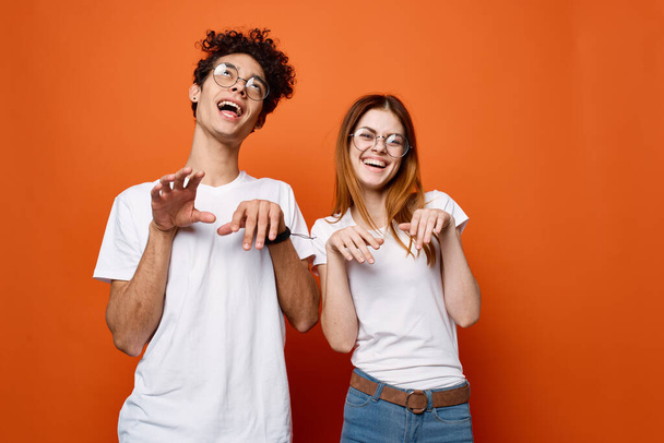 giovane coppia in bianco t-shirt divertimento emozioni arancio sfondo - Foto, immagini