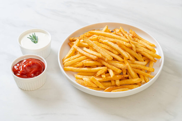 French fries or potato chips with sour cream and ketchup - Foto, Bild