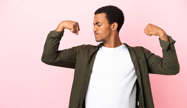 Афроамериканец на розовом фоне делает сильный жест - Фото, изображение