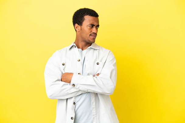 Afro-americano bell'uomo su sfondo giallo isolato mantenendo le braccia incrociate - Foto, immagini