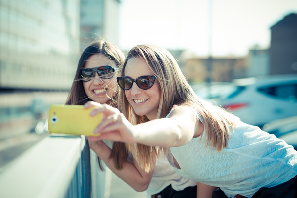 Дві жінки використовують смартфон
 - Фото, зображення