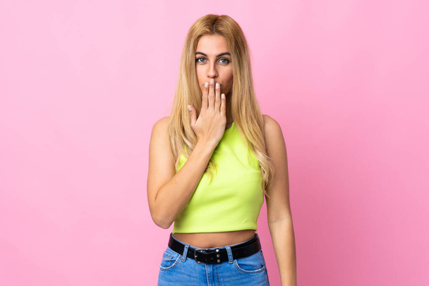 Young Uruguayan blonde woman over isolated pink background covering mouth with hand - Fotó, kép