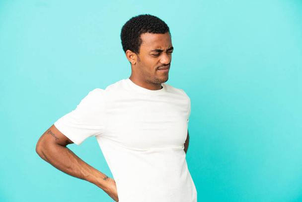 Afrikai amerikai jóképű férfi elszigetelt kék háttér szenved hátfájás, amiért tett egy erőfeszítést - Fotó, kép