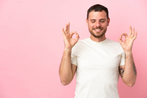 Young Brazilian man isolated on pink background in zen pose - Photo, Image