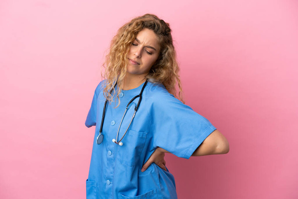 Young surgeon doctor woman isolated on pink background suffering from backache for having made an effort - Photo, Image