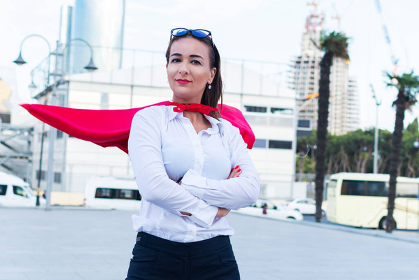 erfolgreiche Geschäftsfrau mit Superhelden-Umhang vor dem Hintergrund der Stadt - Foto, Bild