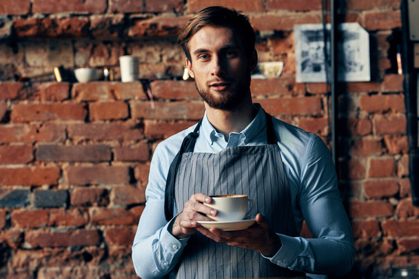 masculino garçom avental café xícara tijolo parede restaurante serviço - Foto, Imagem