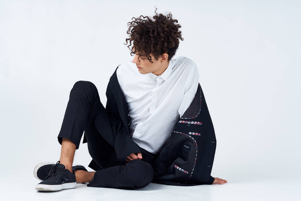 Mann sitzt auf dem Boden lockige Haare Anzug modernen Stil  - Foto, Bild