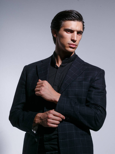 Imagen de un atractivo joven fuerte en traje negro completamente elegante, aislado sobre un fondo blanco. - Foto, imagen