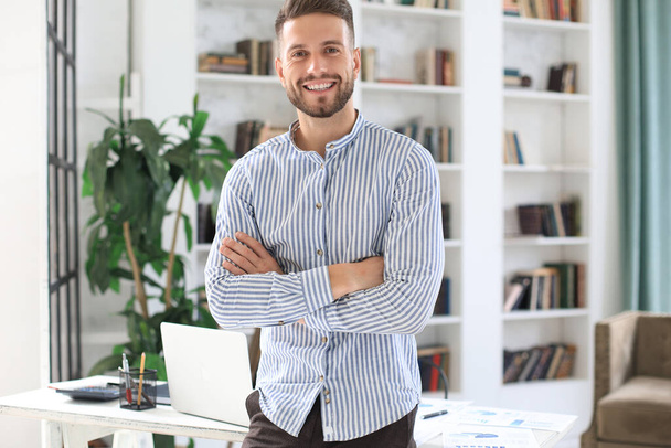 Portrait of happy businessman with arms crossed standing in office - Foto, afbeelding