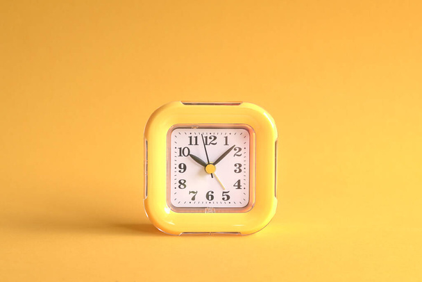 Yellow clock on yellow background. Center of the frame. - Photo, image