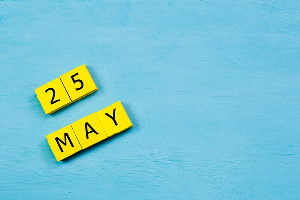 Yellow cubes calendar on blue wooden surface with 25 MAY and copy space - Photo, Image