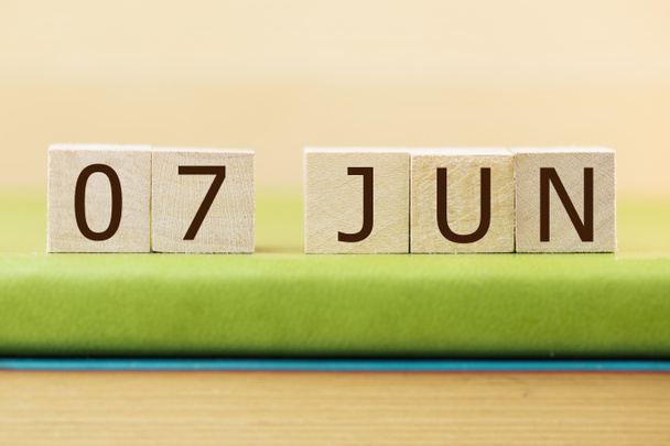 Wooden cubes calendar for 07 JUNE on green book, closeup - 写真・画像