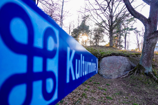 Estocolmo, Suécia Um sinal de rua dizendo em sueco "artefato cultural" aponta para uma antiga pedra runa em um parque. - Foto, Imagem