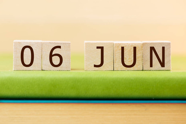 Wooden cubes calendar for 06 JUNE on green book, closeup - 写真・画像