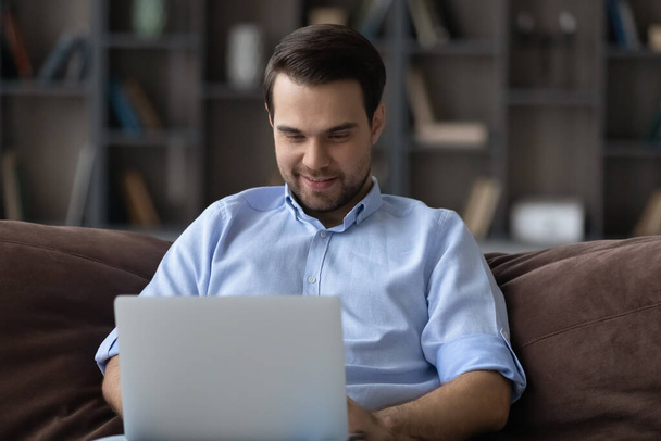 Happy Caucasian man work on laptop at home - Фото, зображення