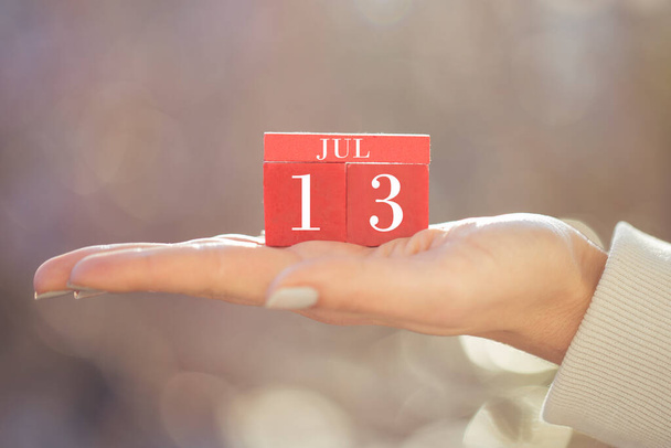 Detailní záběr ženské ruky držící červený dřevěný kalendář. Červené dřevěné kostky kalendář pro Červen 13 - Fotografie, Obrázek