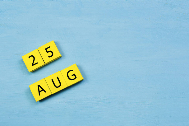 Yellow cubes calendar on blue wooden surface with 25 AUGUST and copy space - Photo, Image