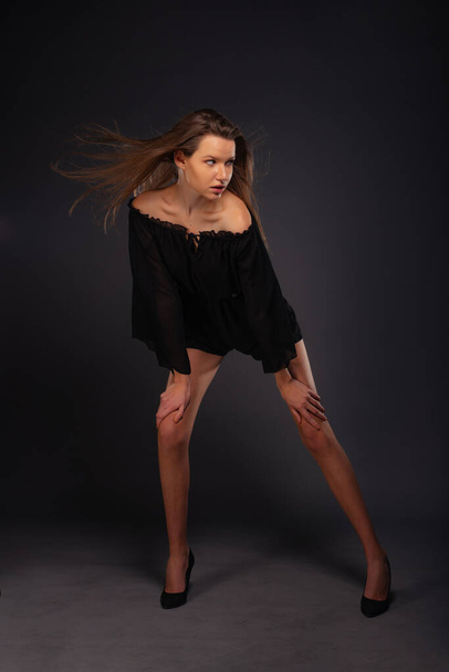 Повнометражна картина привабливої сексуальної молодої жіночої моделі позує ізольовано на темному тлі з чорним платтям
 - Фото, зображення