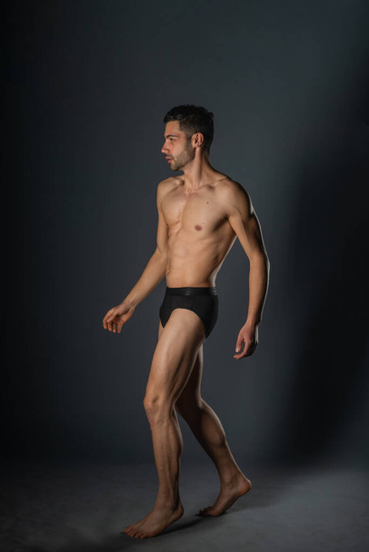 Homem sexy com um corpo muscular posando nu com cuecas pretas dentro de um estúdio - Foto, Imagem