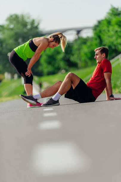 Jeune couple caucasien prenant une pause sur la piste de course et se reposant après avoir couru. - Photo, image