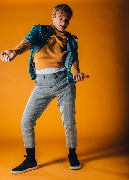 Мускулистый танцор исполняет танцевальный номер в оранжевой студии - Фото, изображение