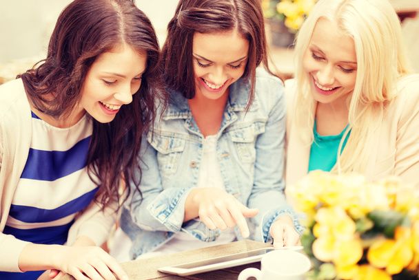 drei schöne Mädchen schauen auf Tablet-PC im Café - Foto, Bild