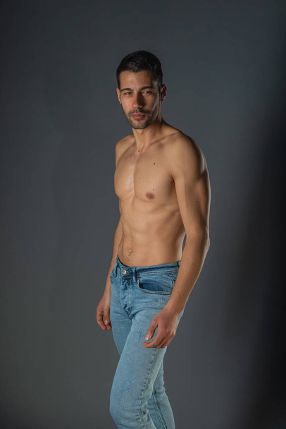 Portrait studio d'un homme sexy torse nu avec abdos en jean bleu denim - Photo, image