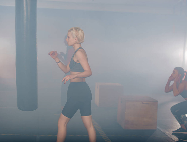 白煙を背にボクシングの練習をしている若い女性のサイドビューの肖像画 - 写真・画像