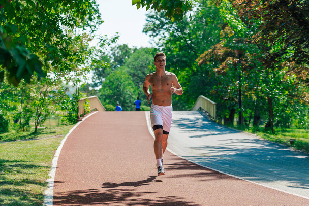 Сильний привабливий чоловік біжить без сорочки на вулиці в парку
 - Фото, зображення
