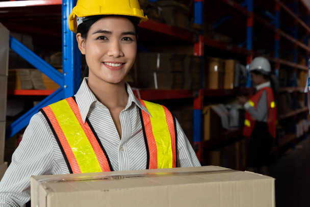 Портрет молодой азиатки, работающей на складе, улыбающейся на складе - Фото, изображение