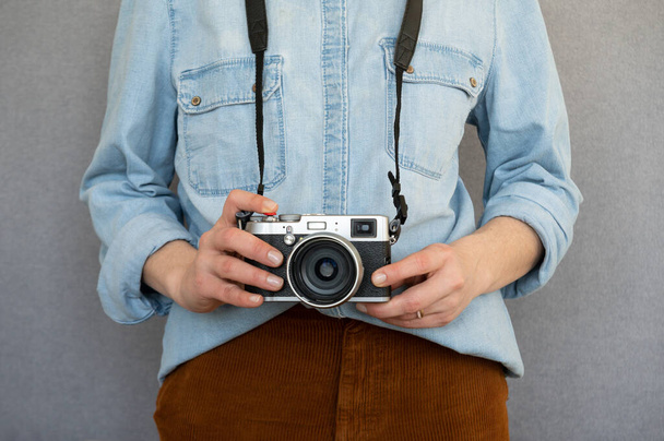 Primer plano de la mujer fresca con ropa casual que sostiene una cámara de estilo vintage. Aislado sobre fondo gris - Foto, Imagen