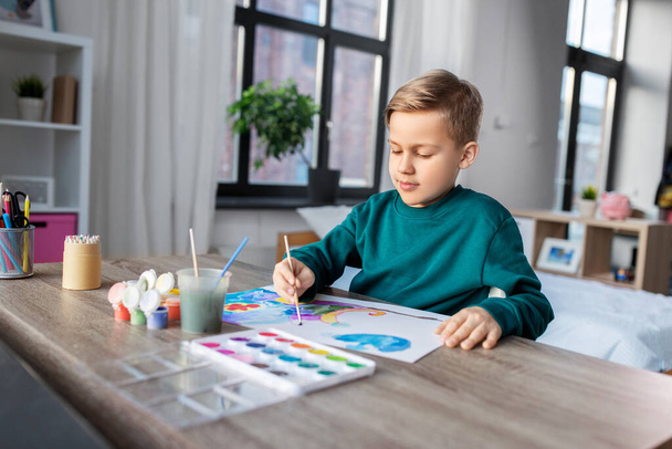 boy with colors and brush drawing picture at home - Foto, Imagem