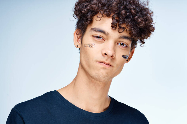 Homme joyeux avec des cosmétiques pour cheveux bouclés sur la peau propre du visage - Photo, image