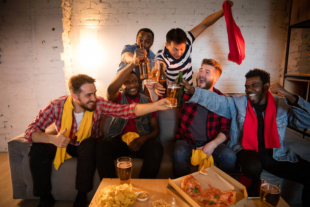 Group of friends watching TV, sport match together. Emotional fans cheering for favourite team, watching on exciting game. Concept of friendship, leisure activity, emotions - Foto, Imagem